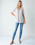 Woman wearing a patterned blouse and blue jeans on a white background