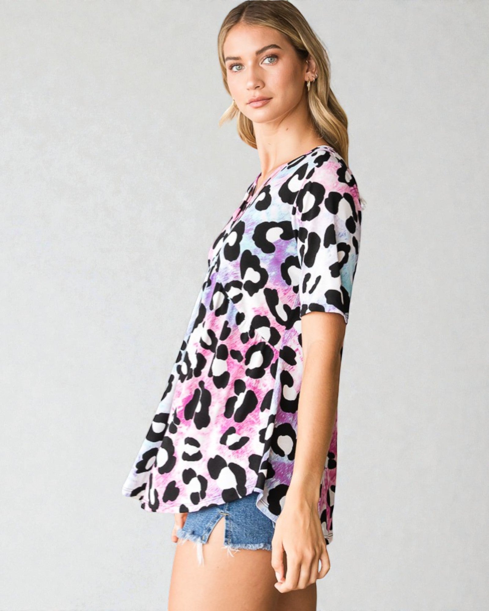 Woman wearing a colorful leopard print top on a gray background