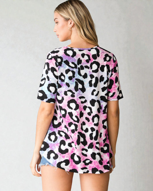 Person wearing a colorful leopard print top on a plain background