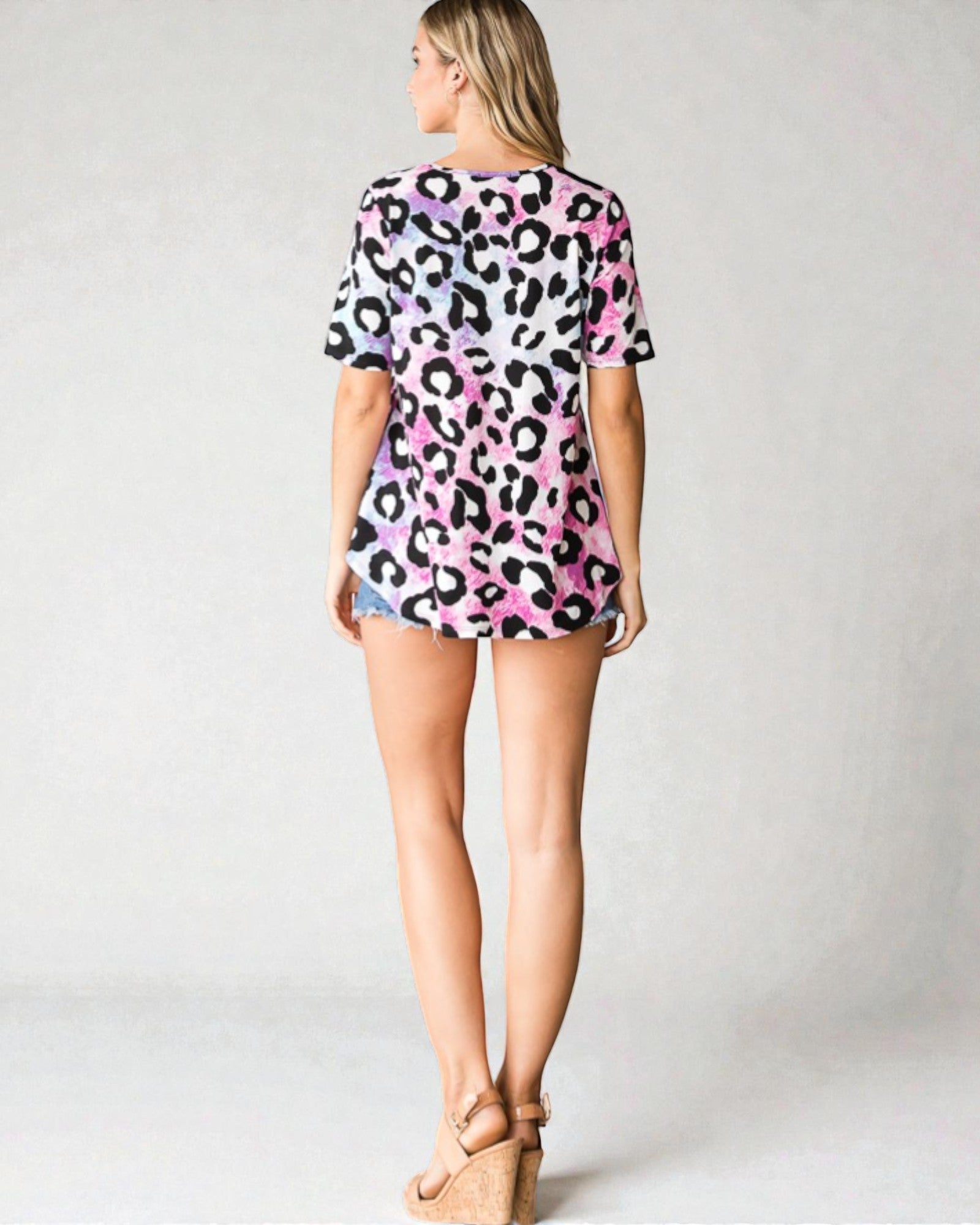 Woman wearing a pink leopard print dress on a plain background