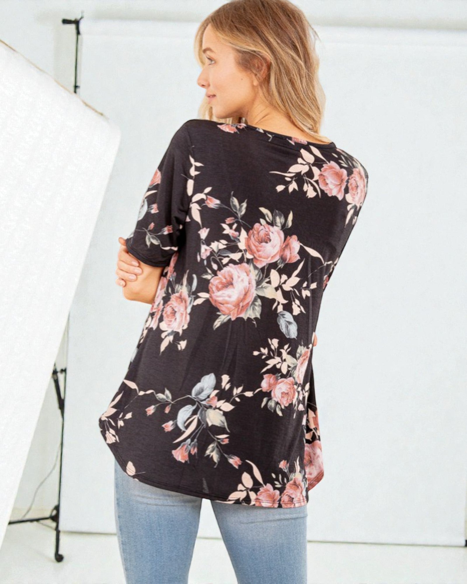 Woman wearing a black floral long-sleeve top against a white background