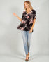 Woman wearing a black floral top and light blue jeans on a gray background