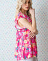 Woman wearing a pink floral dress against a colorful heart-patterned background