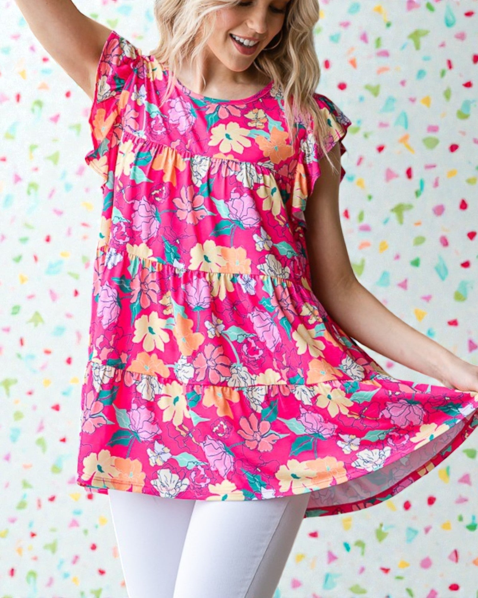 Woman wearing a bright pink floral dress against a colorful heart-patterned background