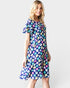Woman wearing a colorful floral dress on a plain background