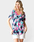 Woman wearing a colorful floral blouse with a pink neckline on a white background