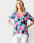 Woman wearing a colorful floral top with a plain background