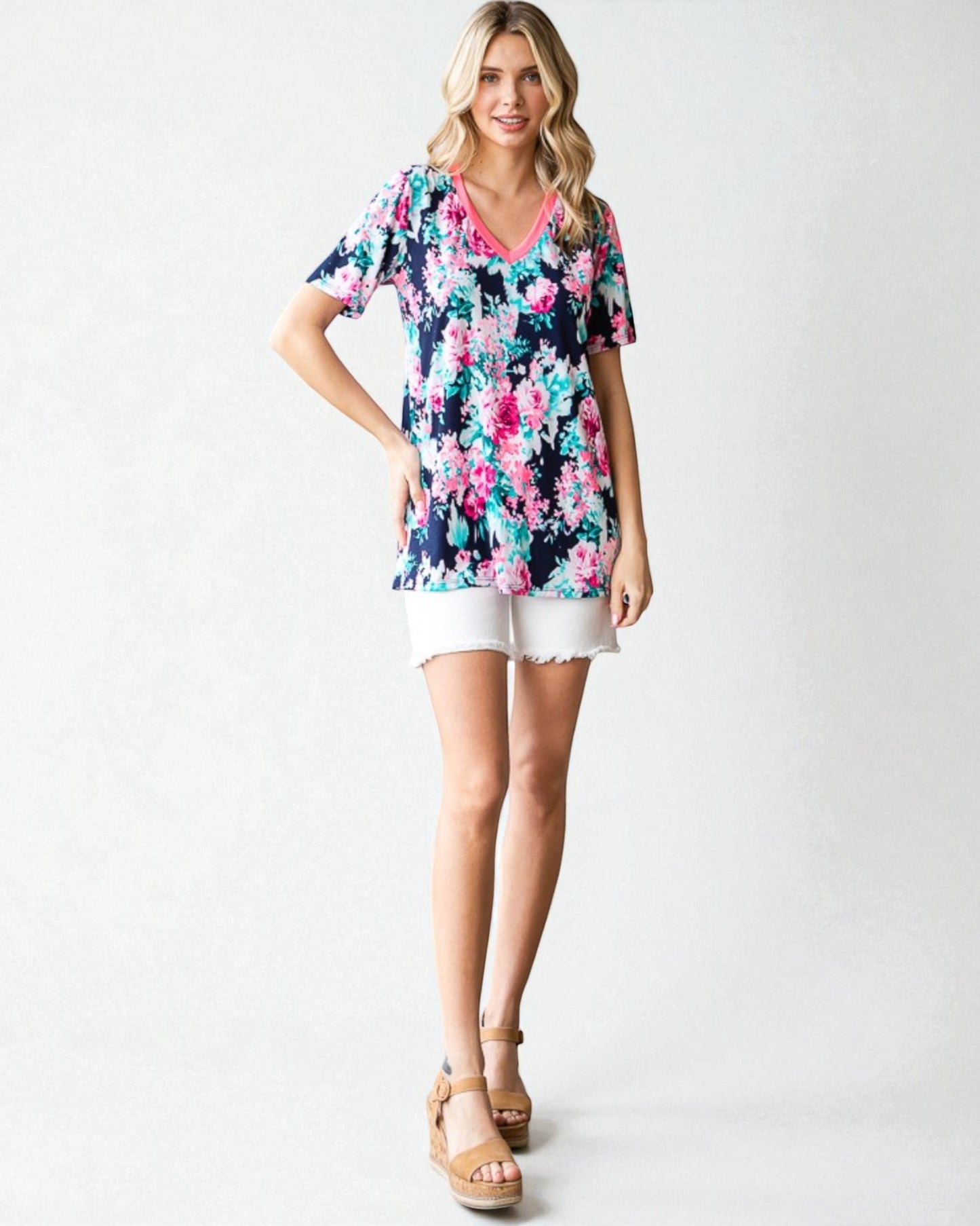 Woman wearing a floral top and white shorts on a white background