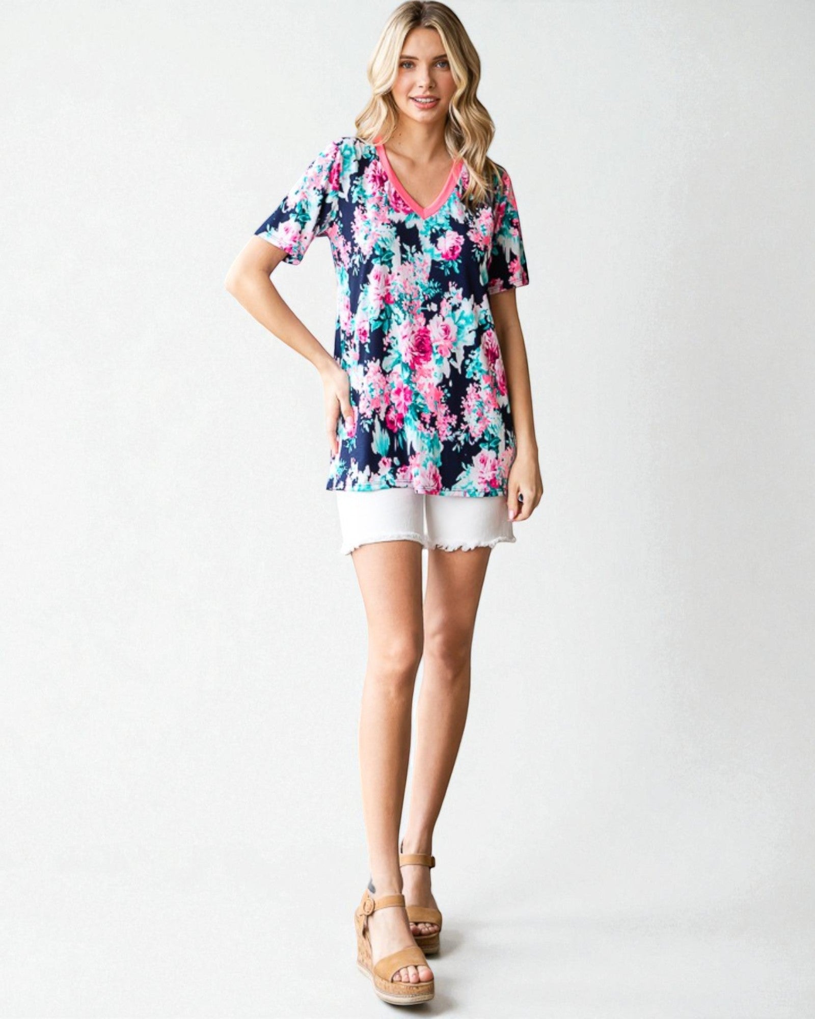 Woman wearing a floral top and white shorts on a white background