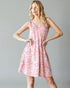 Woman wearing a pink floral dress against a gray background