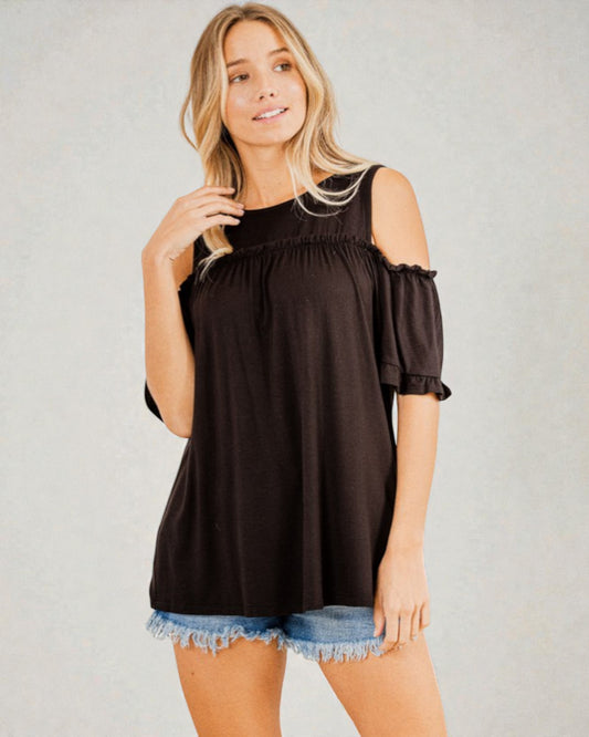 Woman wearing a black off-shoulder top with denim shorts on a gray background