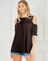 Woman wearing a black cold-shoulder top with ruffled sleeves against a white background