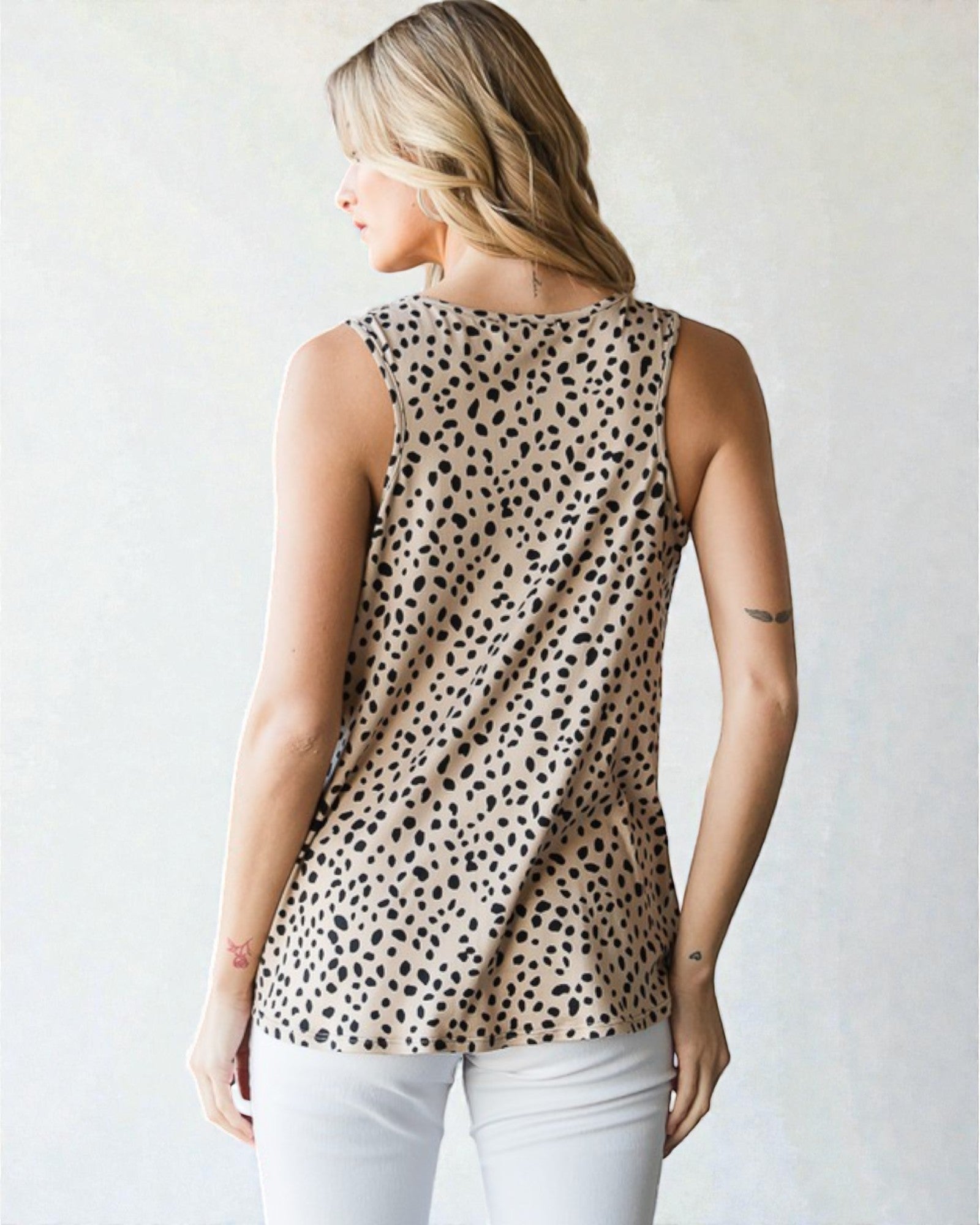 Woman wearing a sleeveless top with a leopard print pattern against a plain background