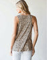 Woman wearing a sleeveless top with a leopard print pattern against a plain background