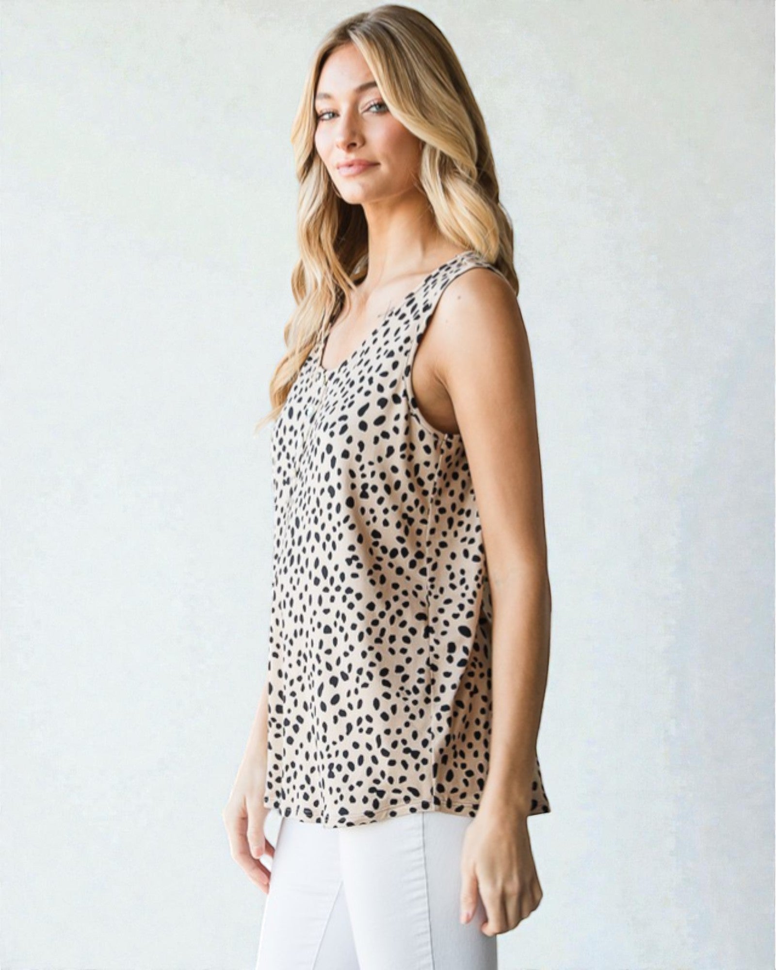 Woman wearing a sleeveless animal print top against a plain background