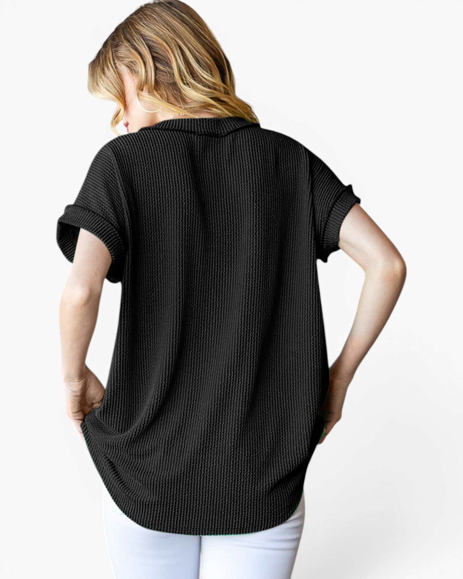 A woman shown from the back wearing a black short-sleeve ribbed knit top and white pants against a plain white background.