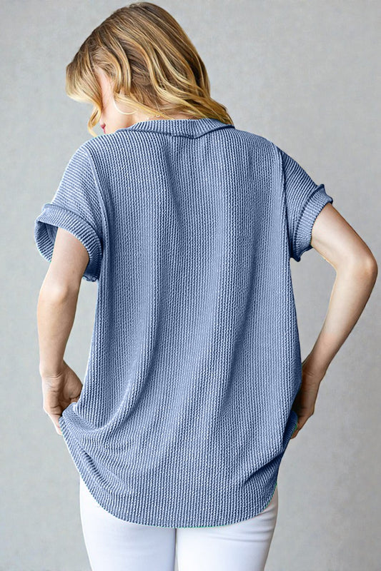 Woman wearing a blue textured shirt against a gray background