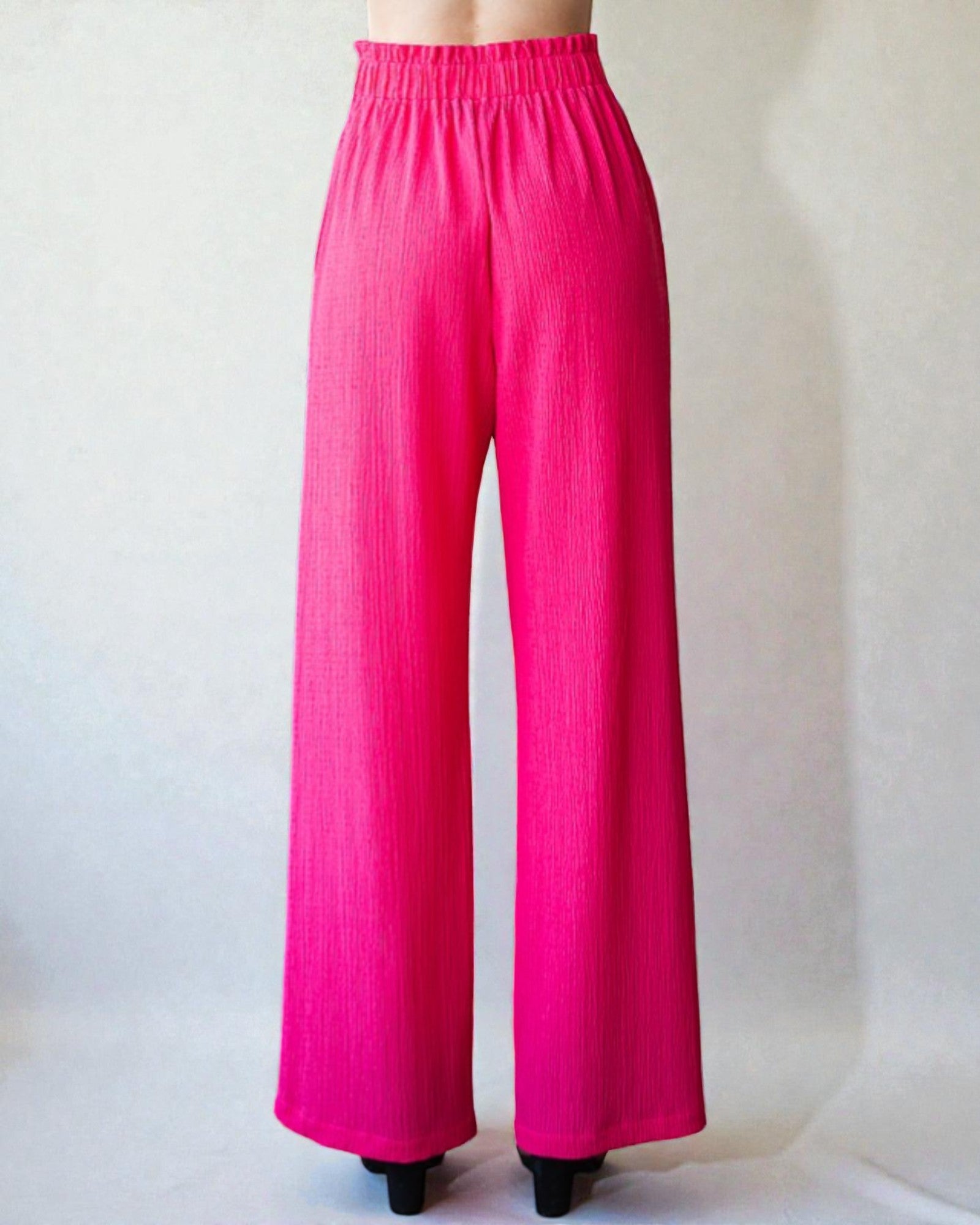 Bright pink wide-leg pants on a plain background