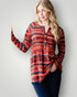 Woman wearing a red patterned long-sleeve shirt against a plain background