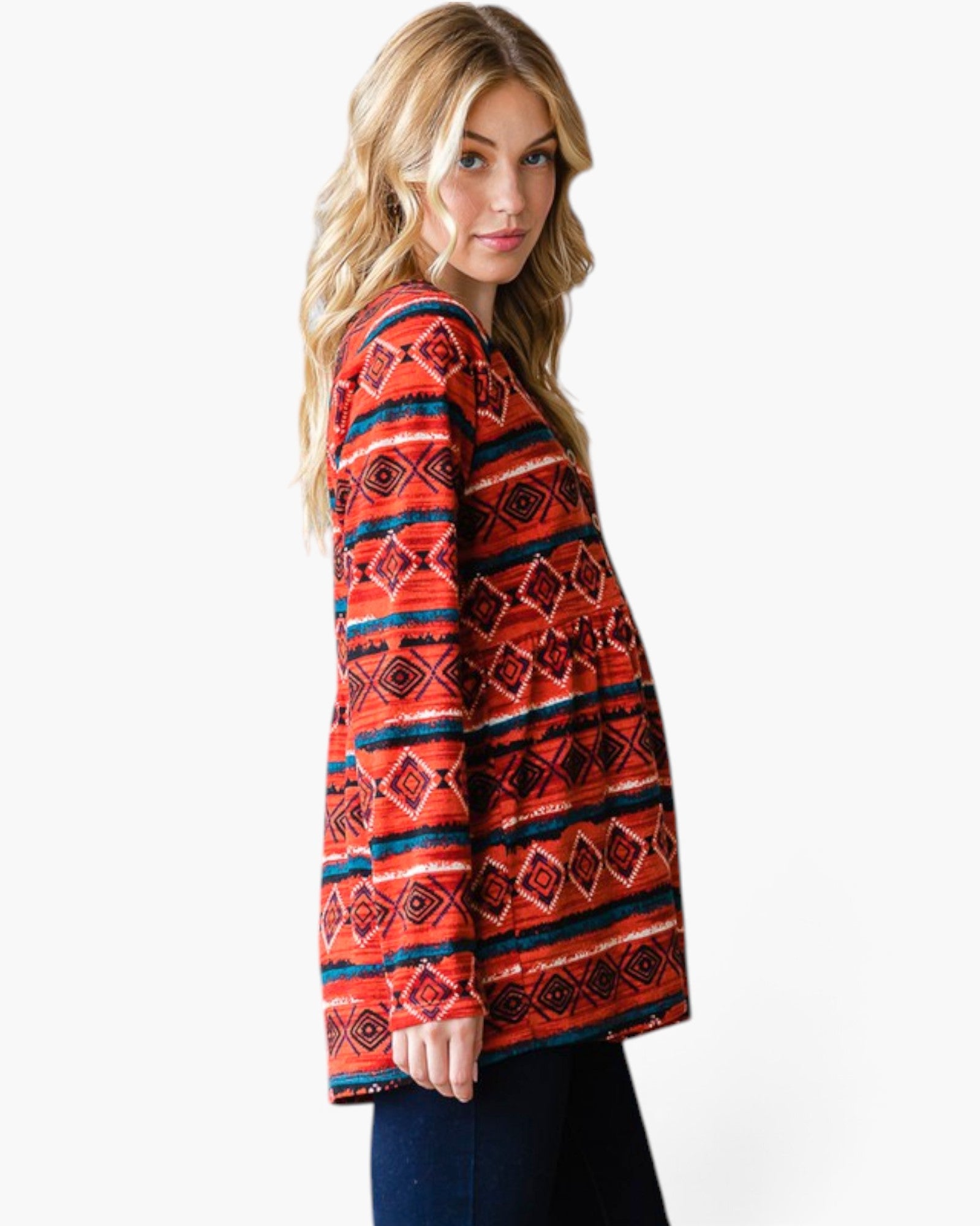 A woman modeling a long-sleeve knit top with a vibrant red, orange, and navy blue geometric pattern, shown from a side-back angle against a plain white background.