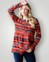 Woman wearing a red patterned long-sleeve shirt against a light gray background