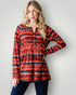 Woman wearing a red and black patterned long-sleeve top against a white background