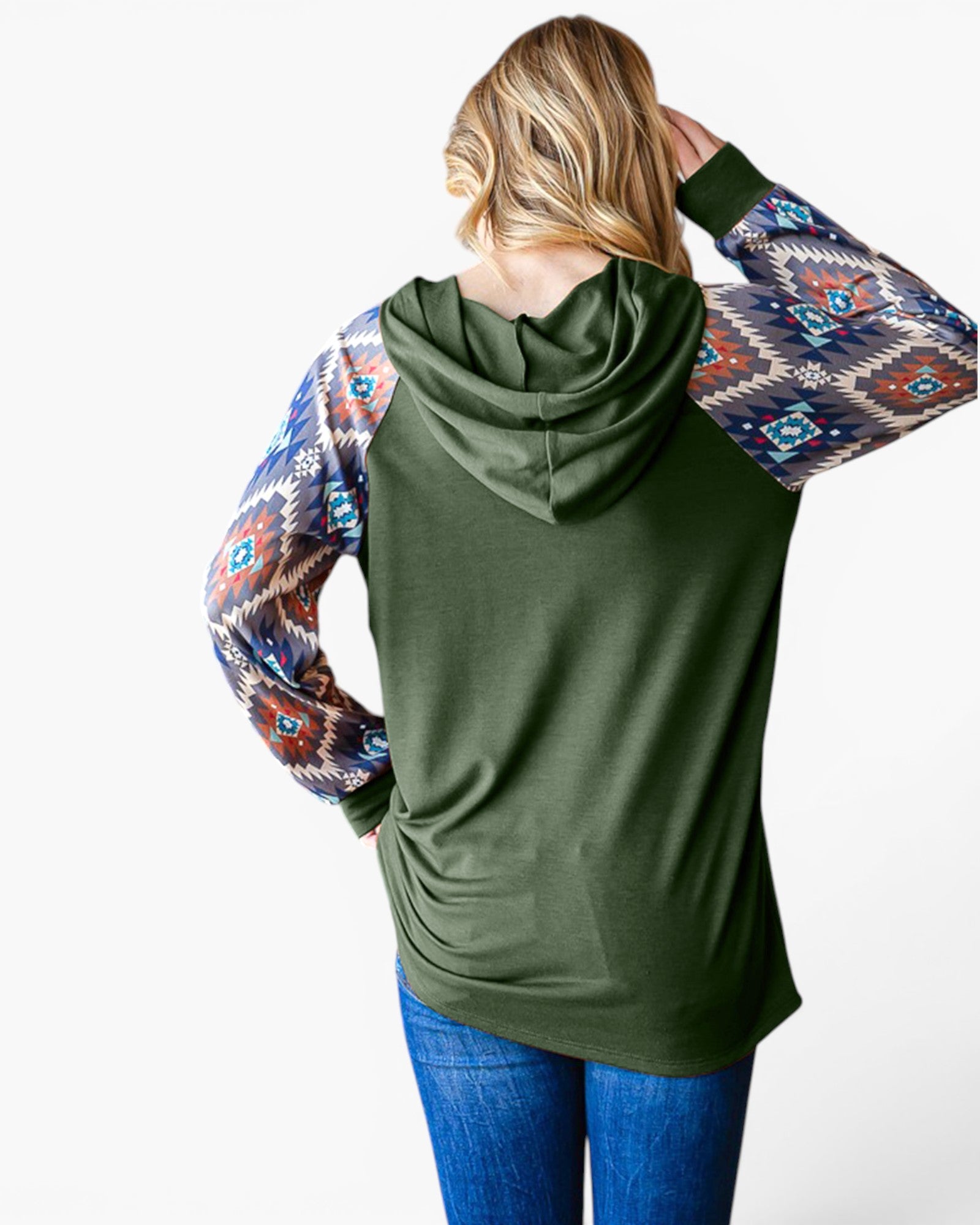 A woman shown from the back wearing an olive green hooded long-sleeve top with patterned raglan sleeves featuring a Southwestern geometric design in blue, red, and beige, paired with blue jeans against a white studio background.