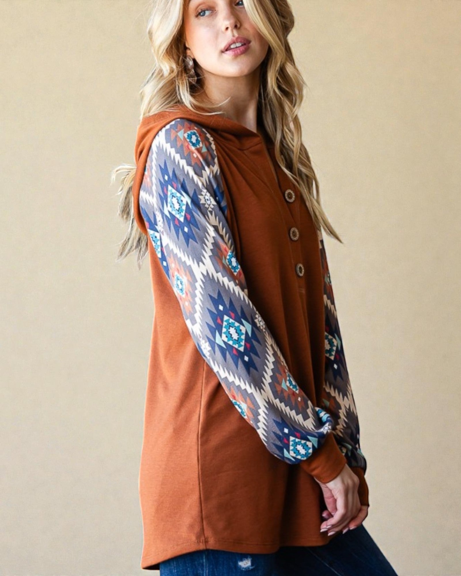 Woman wearing a brown cardigan with a patterned sleeve against a beige background