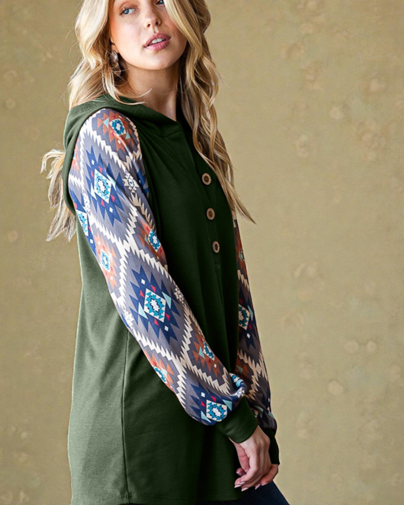 Woman wearing a green dress with a patterned shawl over her shoulders against a beige background