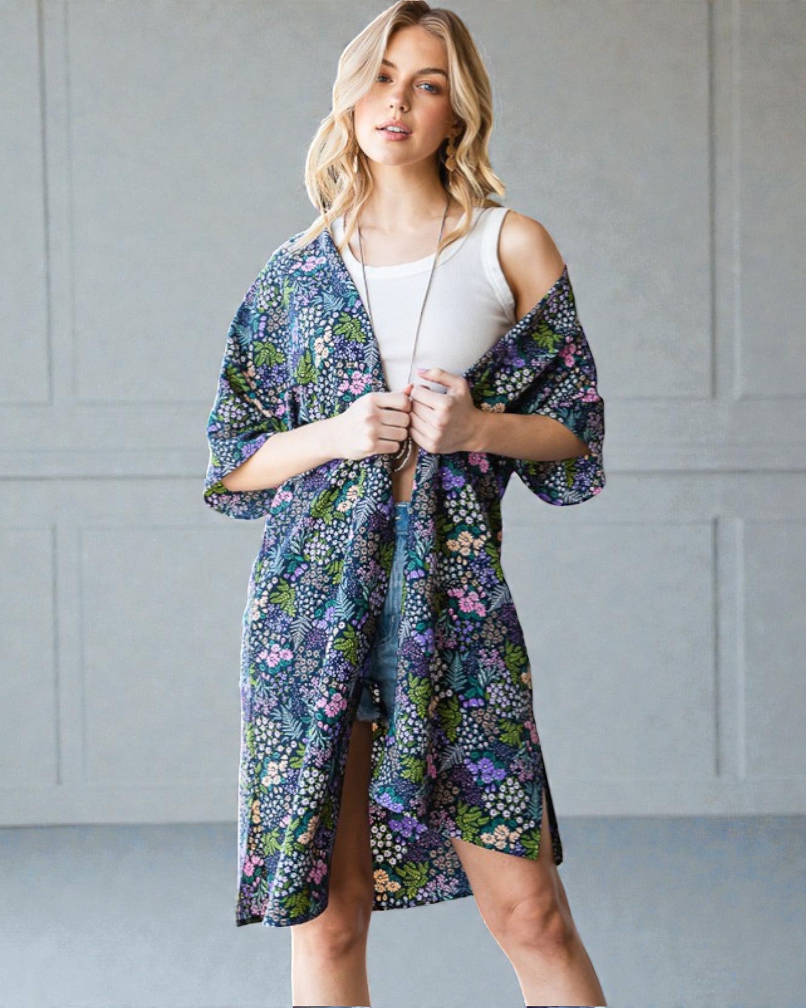 Woman wearing a floral kimono over a white top against a gray background