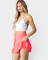 Woman wearing a white crop top and pink skirt on a white background