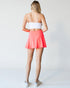 Person wearing a white sports bra and coral skirt on a plain background