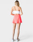 Person wearing a white crop top and coral skirt on a light gray background
