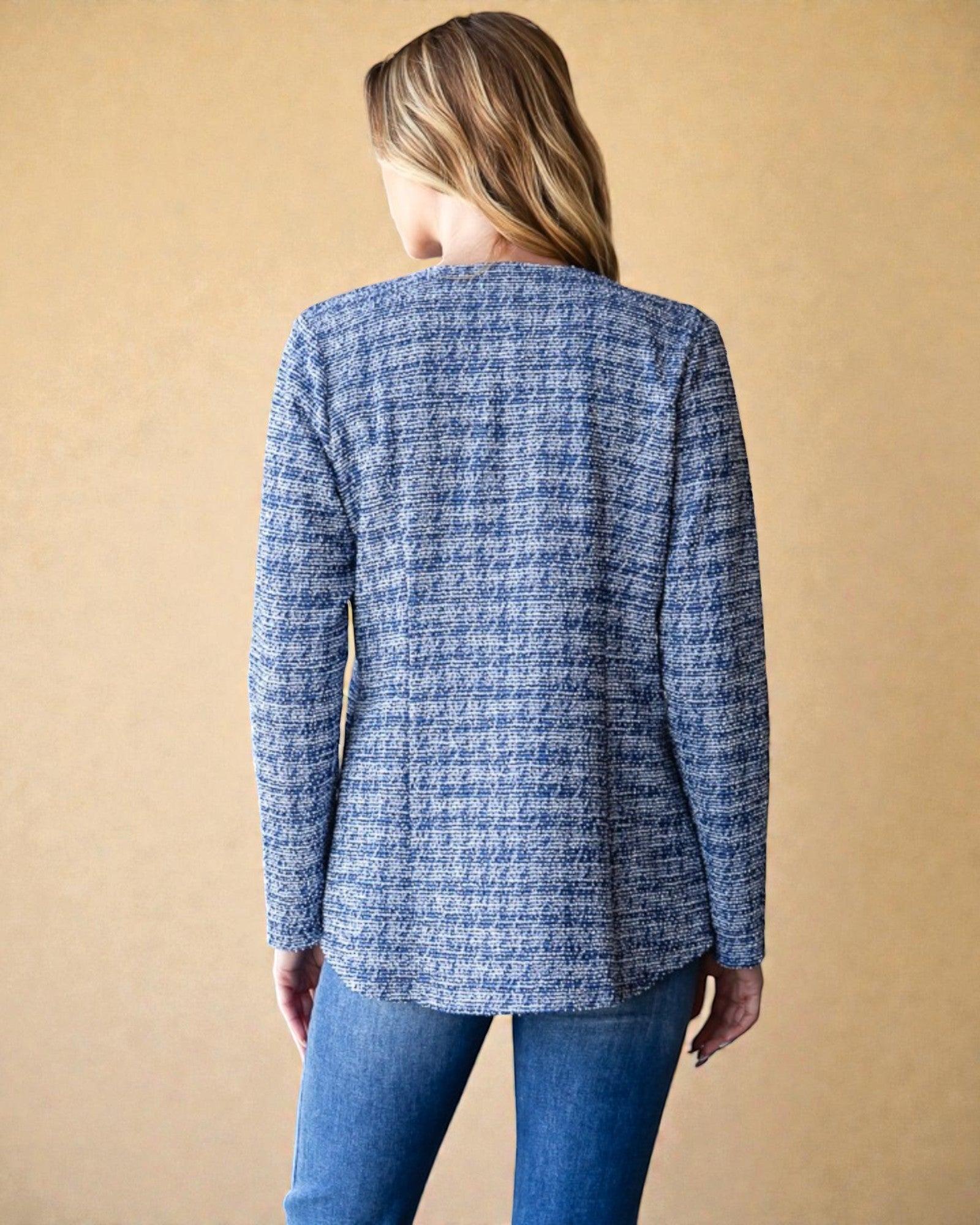 Person wearing a blue textured jacket against a beige background