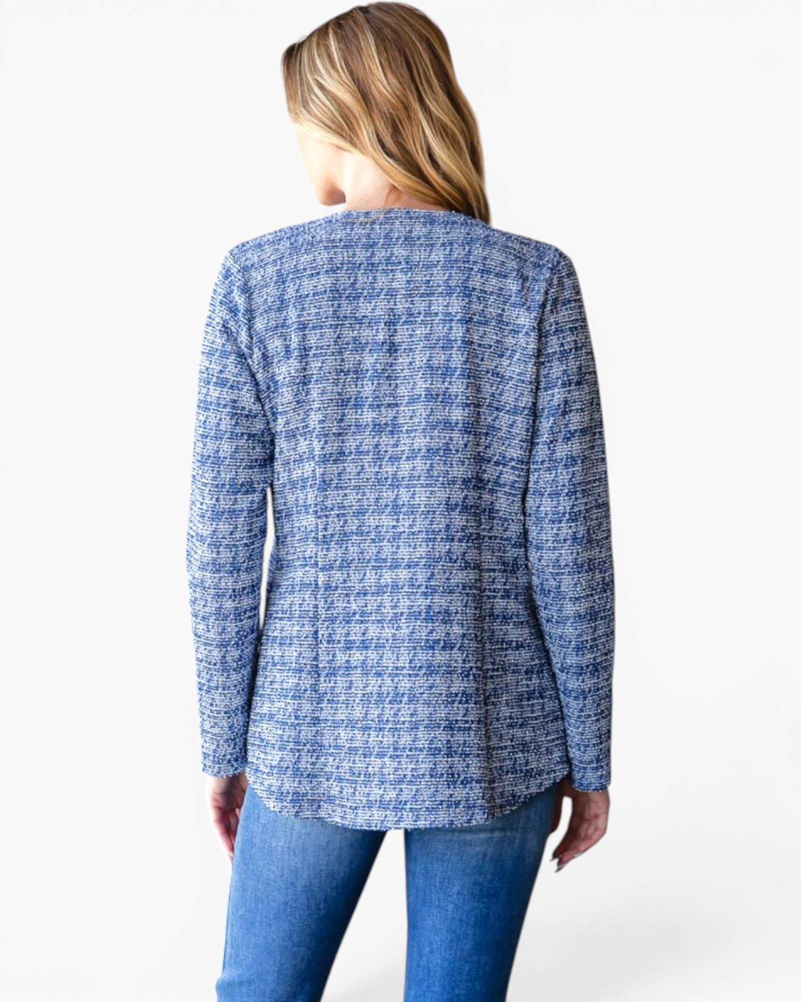 A woman shown from the back wearing a blue and white tweed blazer with blue jeans, photographed against a plain light gray studio background.