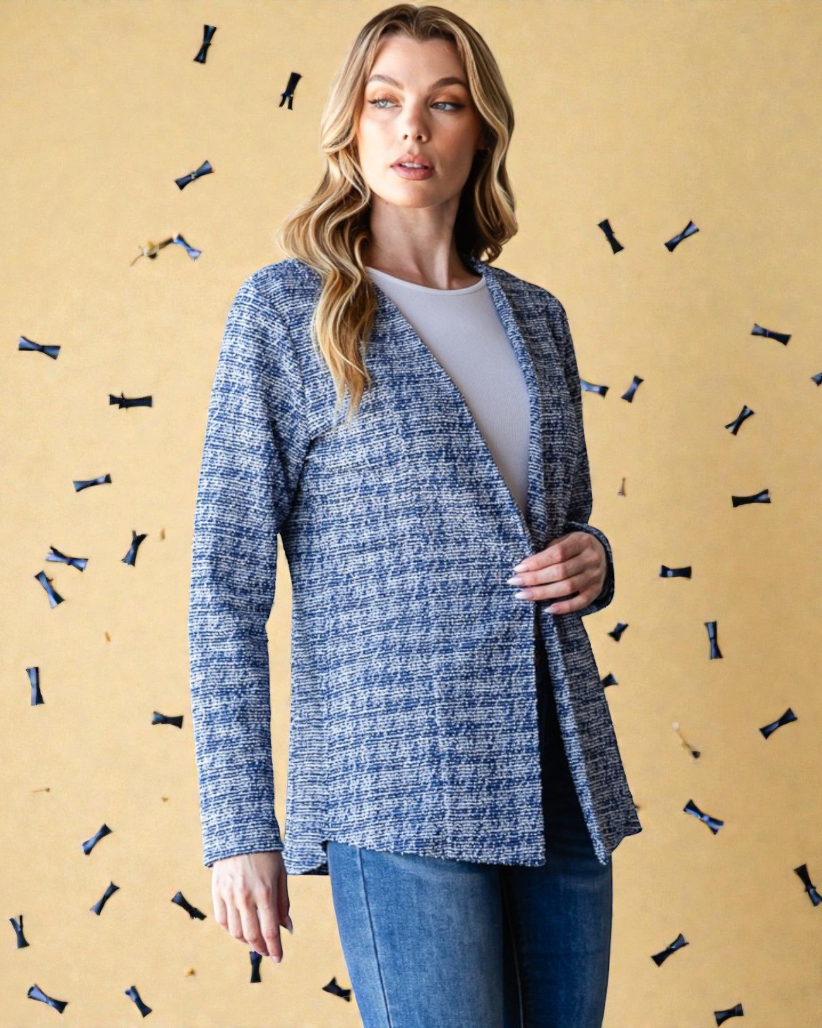 Woman wearing a blue textured blazer over a white shirt with a beige background featuring decorative elements.