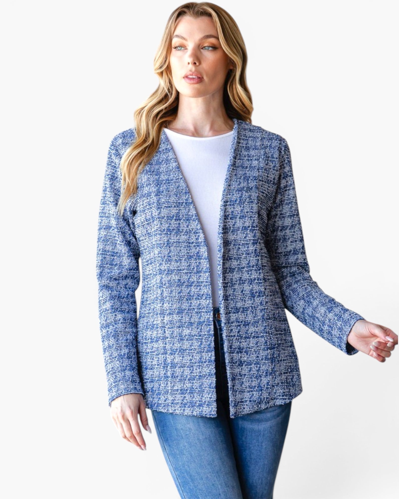 A woman modeling a blue and white textured tweed open-front cardigan over a white top and blue jeans, photographed against a plain light gray studio background.
