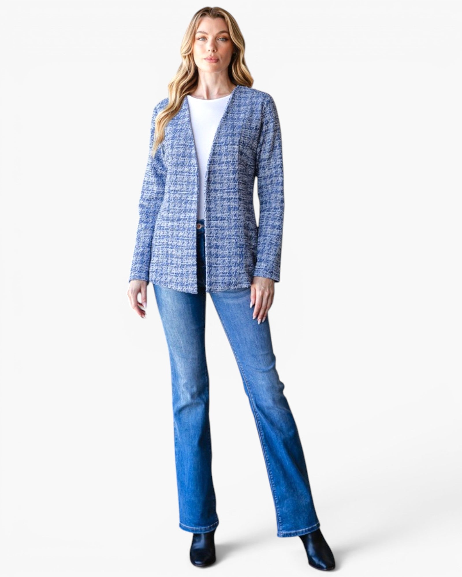 A woman modeling a blue and white patterned tweed blazer over a white top and blue jeans, standing against a plain white studio background.