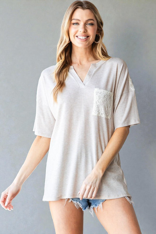 Woman wearing a white oversized shirt with lace detail on a gray background