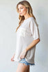 Woman wearing a beige oversized shirt with a pocket on a plain background