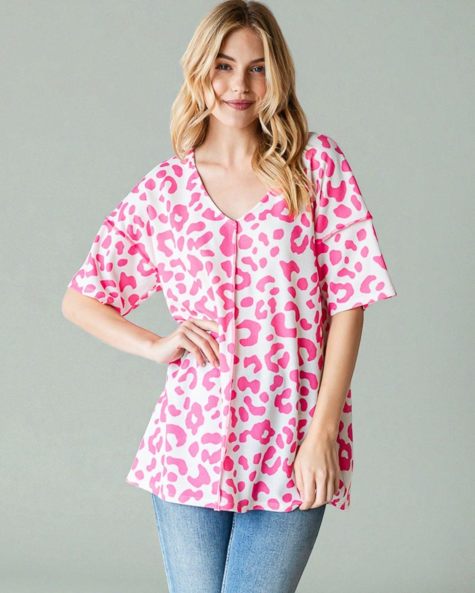 Woman wearing a pink leopard print top against a gray background