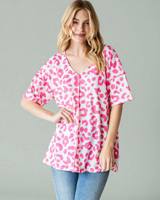 Woman wearing a pink leopard print top against a gray background