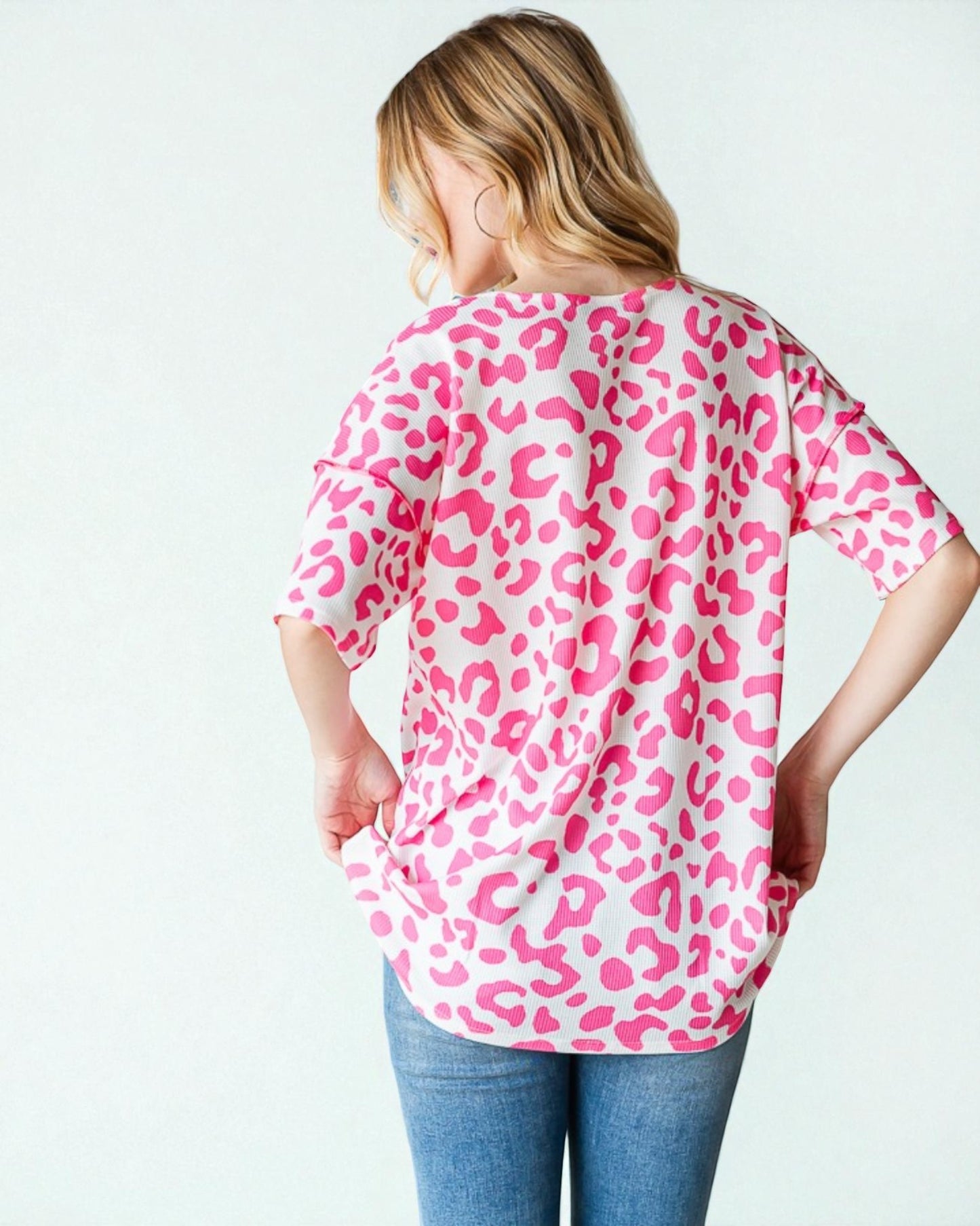 Person wearing a pink leopard print shirt on a white background