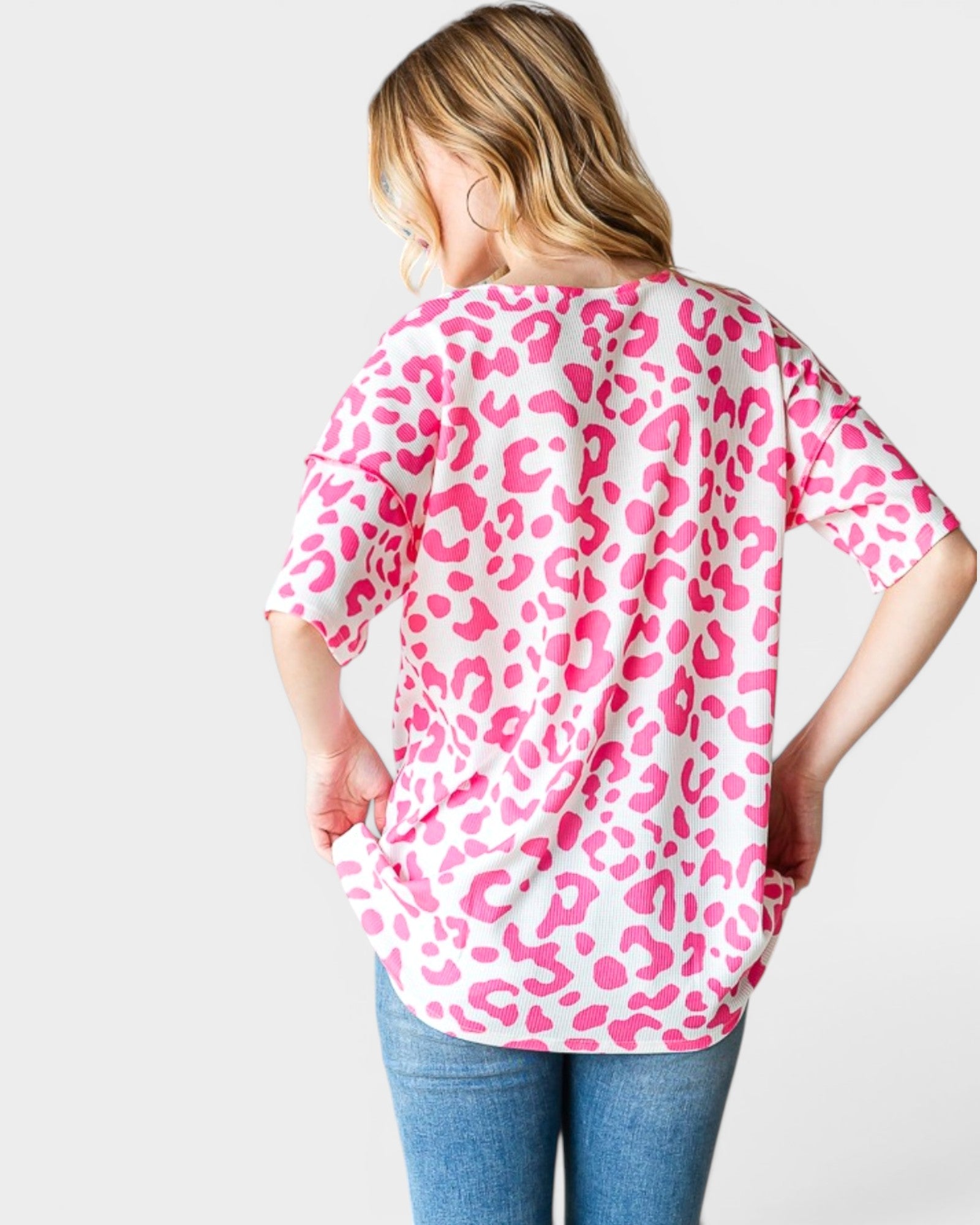 Person wearing a pink leopard print shirt on a white background