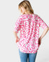 Person wearing a pink leopard print shirt on a white background