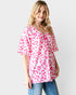 Woman wearing a pink leopard print top and blue jeans on a white background