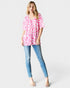 Woman wearing a pink leopard print top and blue jeans on a white background