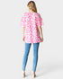 Woman wearing a pink leopard print top and blue jeans on a white background