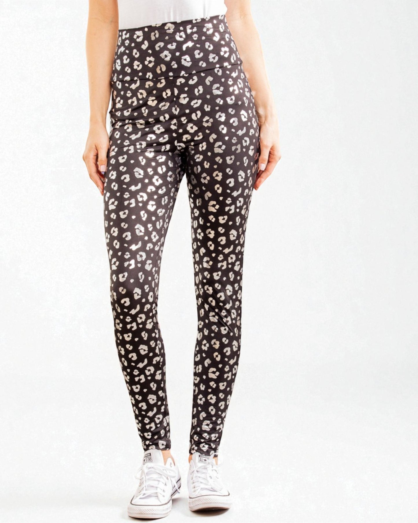 Person wearing black leggings with beige leopard print on a white background