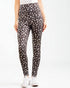 Person wearing black leggings with beige leopard print on a white background